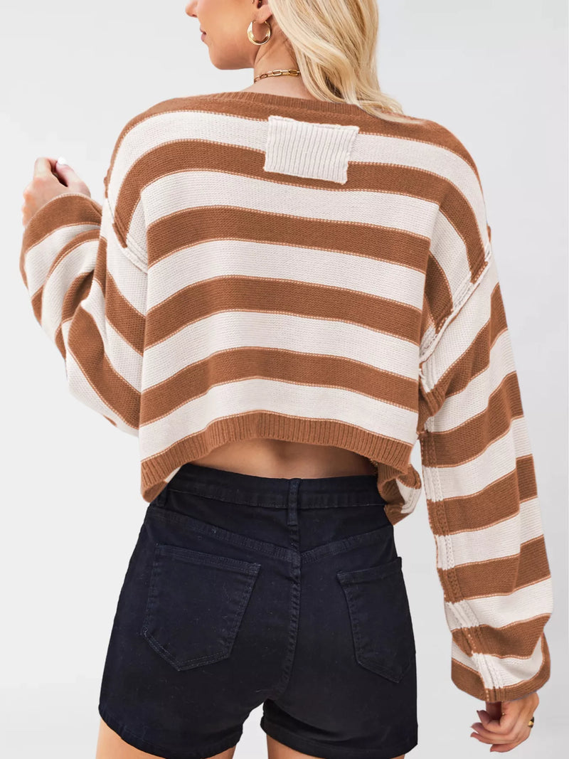 Person wearing a brown and white striped sweater with black shorts on a plain background