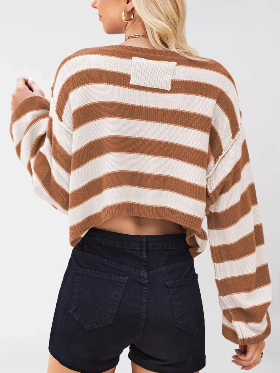 Person wearing a brown and white striped sweater with black shorts on a plain background