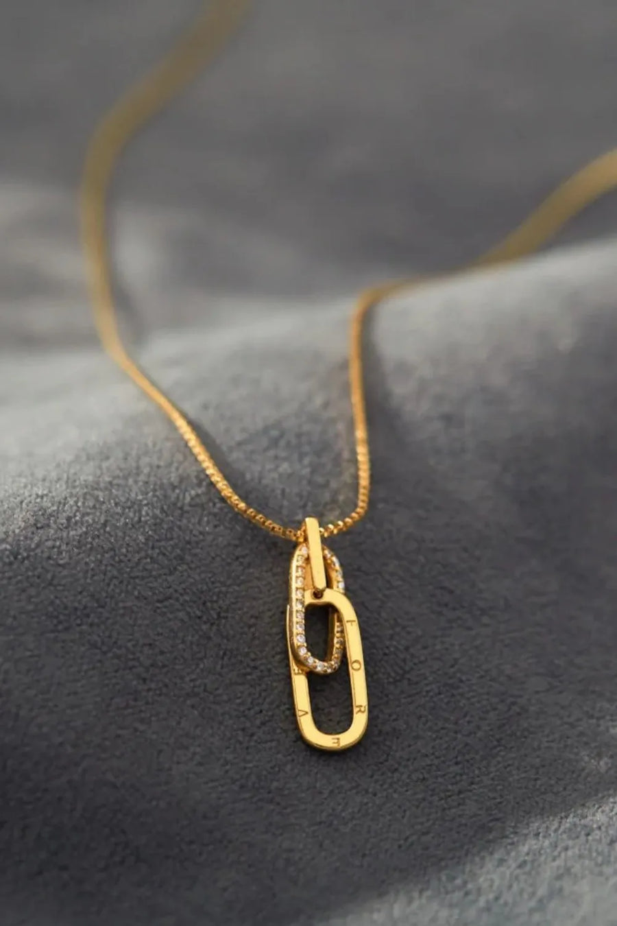 Gold necklace with a pendant on a textured gray surface