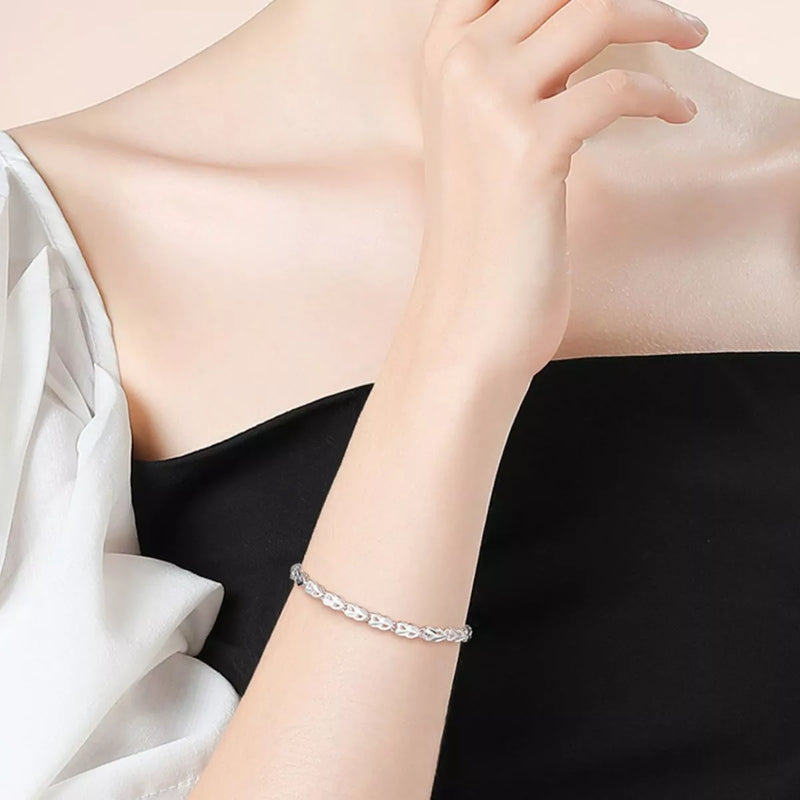 Silver bracelet on a person's wrist with a neutral background