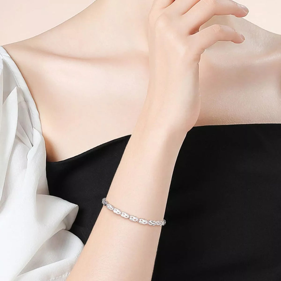 Silver bracelet on a person's wrist with a neutral background