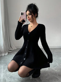 Woman wearing a black dress taking a mirror selfie in a minimalistic room.
