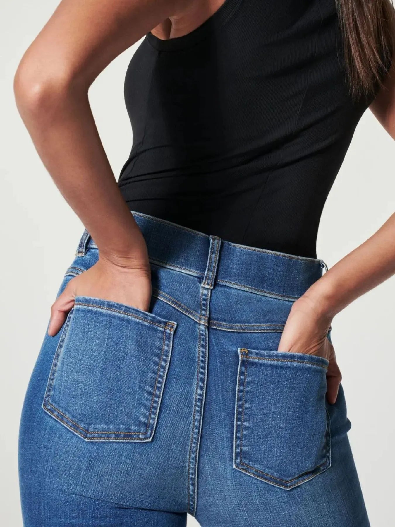 Person wearing blue jeans with a plain background