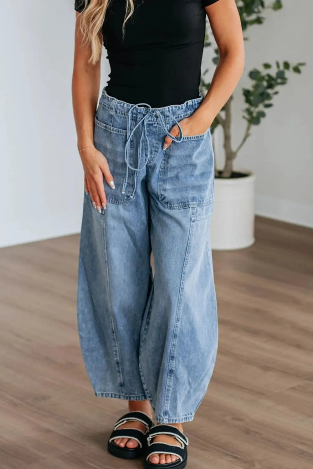 Person wearing wide-leg jeans and a black top indoors.