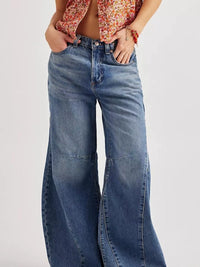 Person wearing blue jeans with a plain background