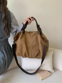 Person holding a brown handbag on a couch with a neutral background
