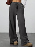 Person wearing gray ribbed knit pants with a plain background