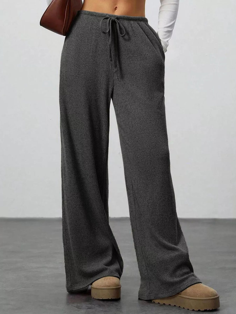 Person wearing gray ribbed knit pants with a plain background