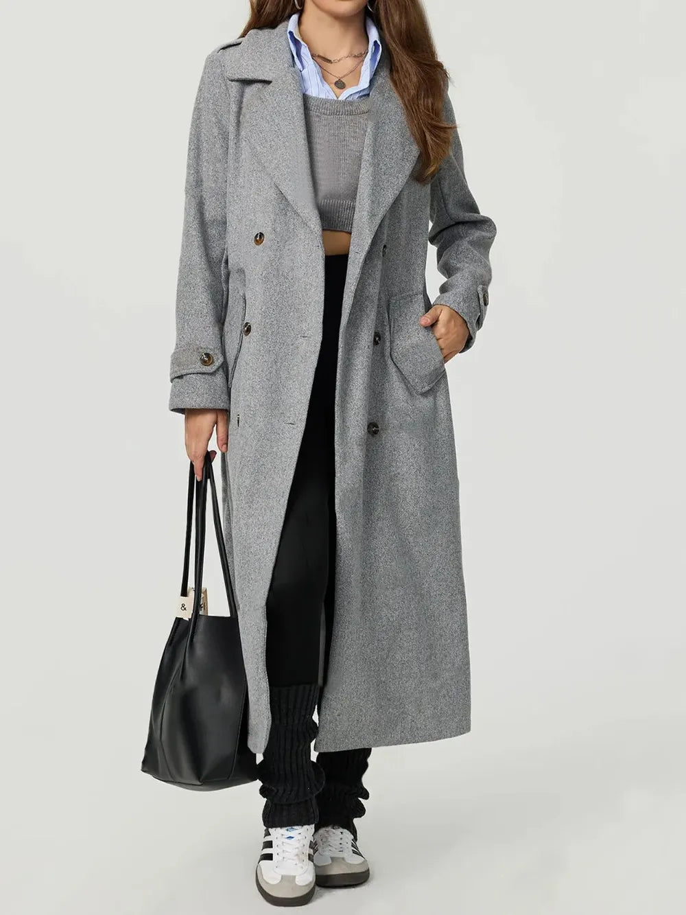 Person wearing a gray coat holding a black bag on a white background