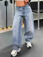 Person wearing blue jeans and white sneakers in an indoor setting