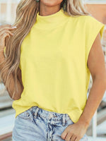 Person wearing a yellow sleeveless top and denim shorts outdoors