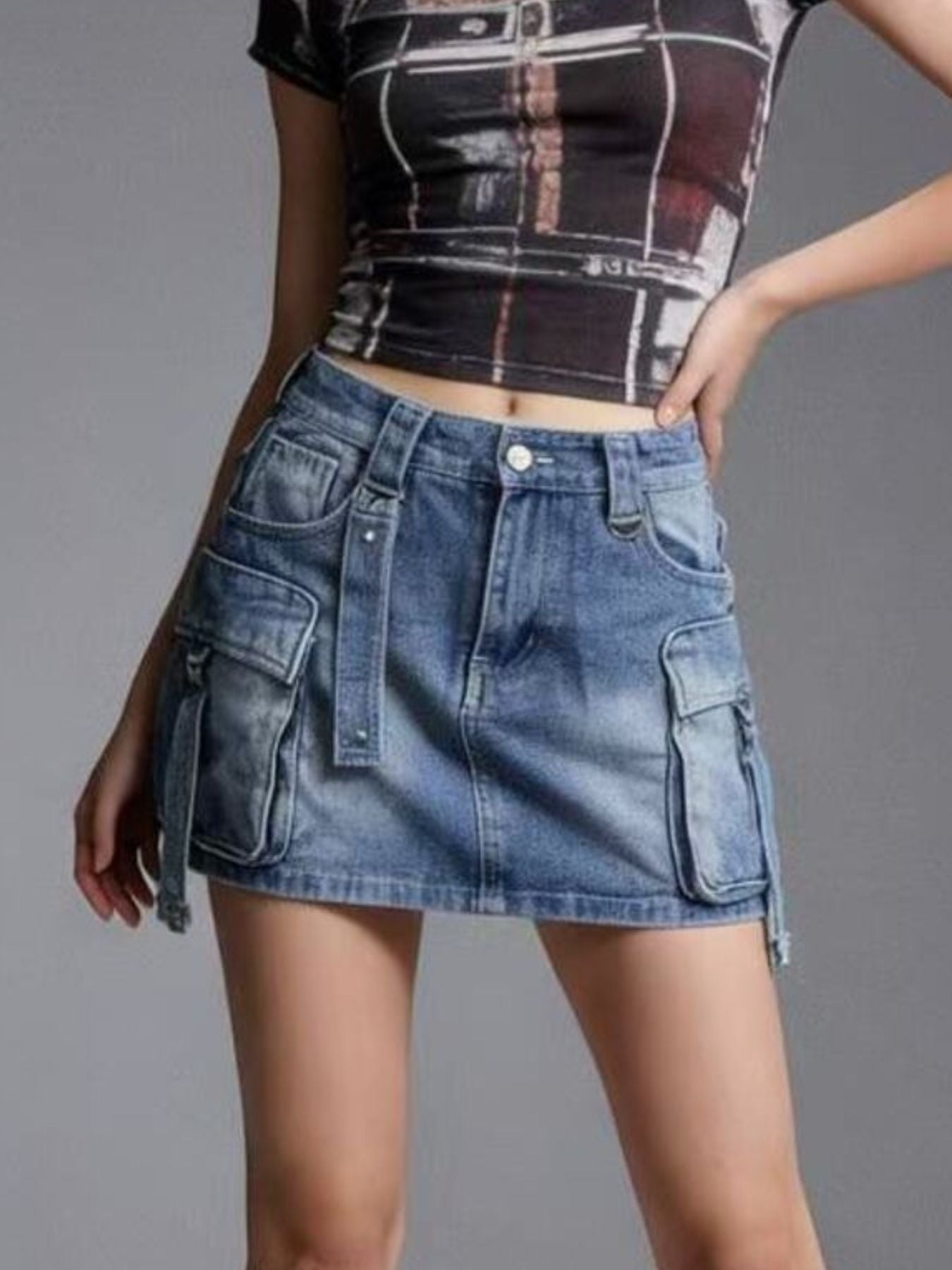 Person wearing a blue denim skirt and a patterned top on a gray background