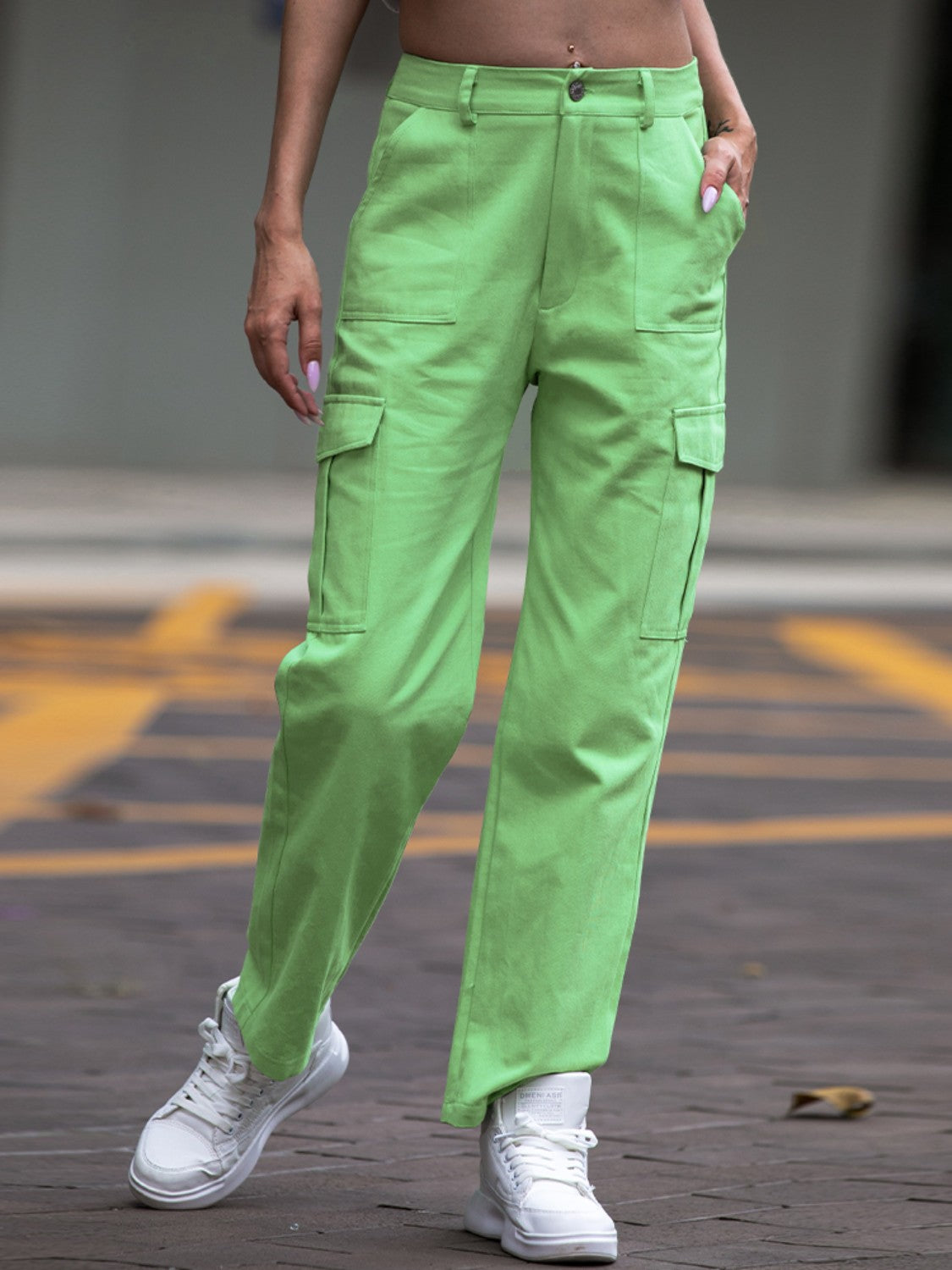 Person wearing bright green cargo pants and white sneakers on a street.