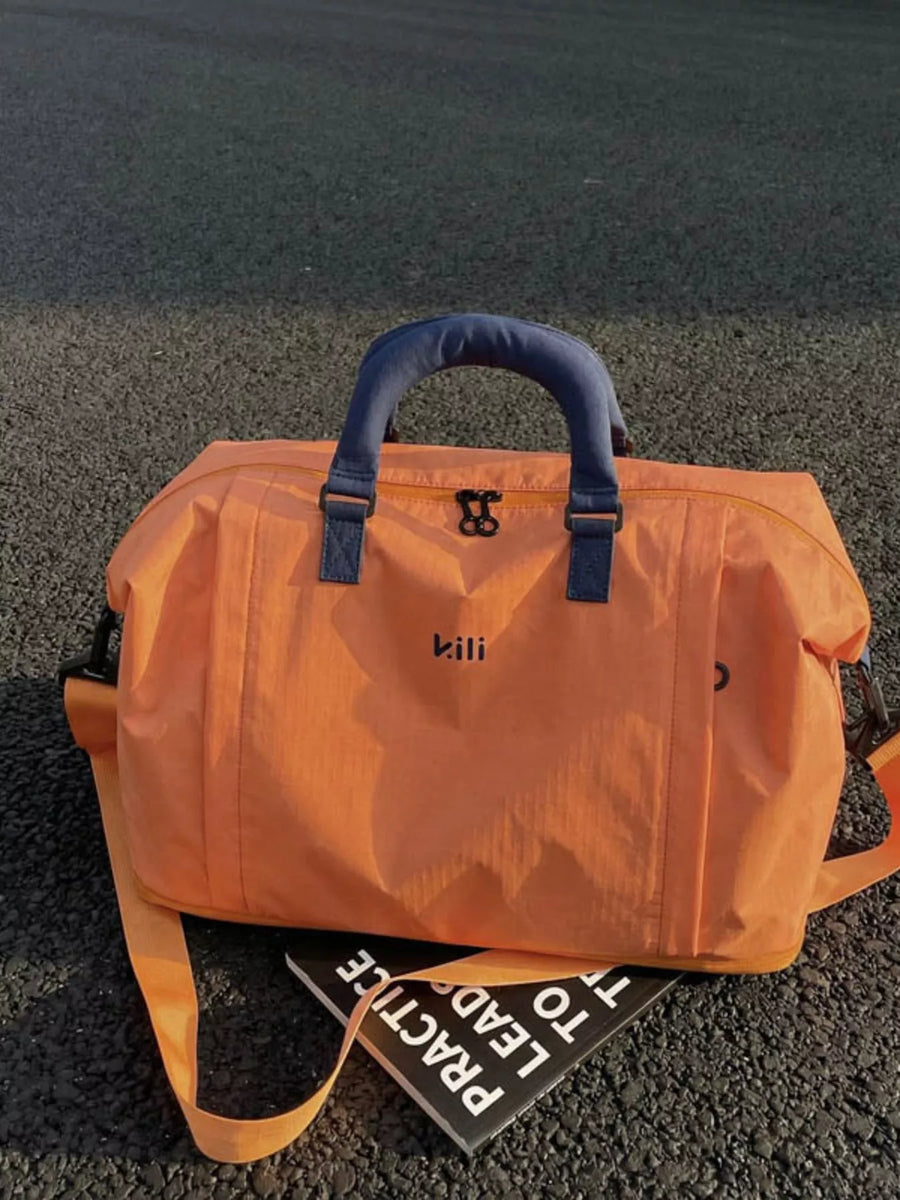 Orange duffel bag with blue handles on a dark surface