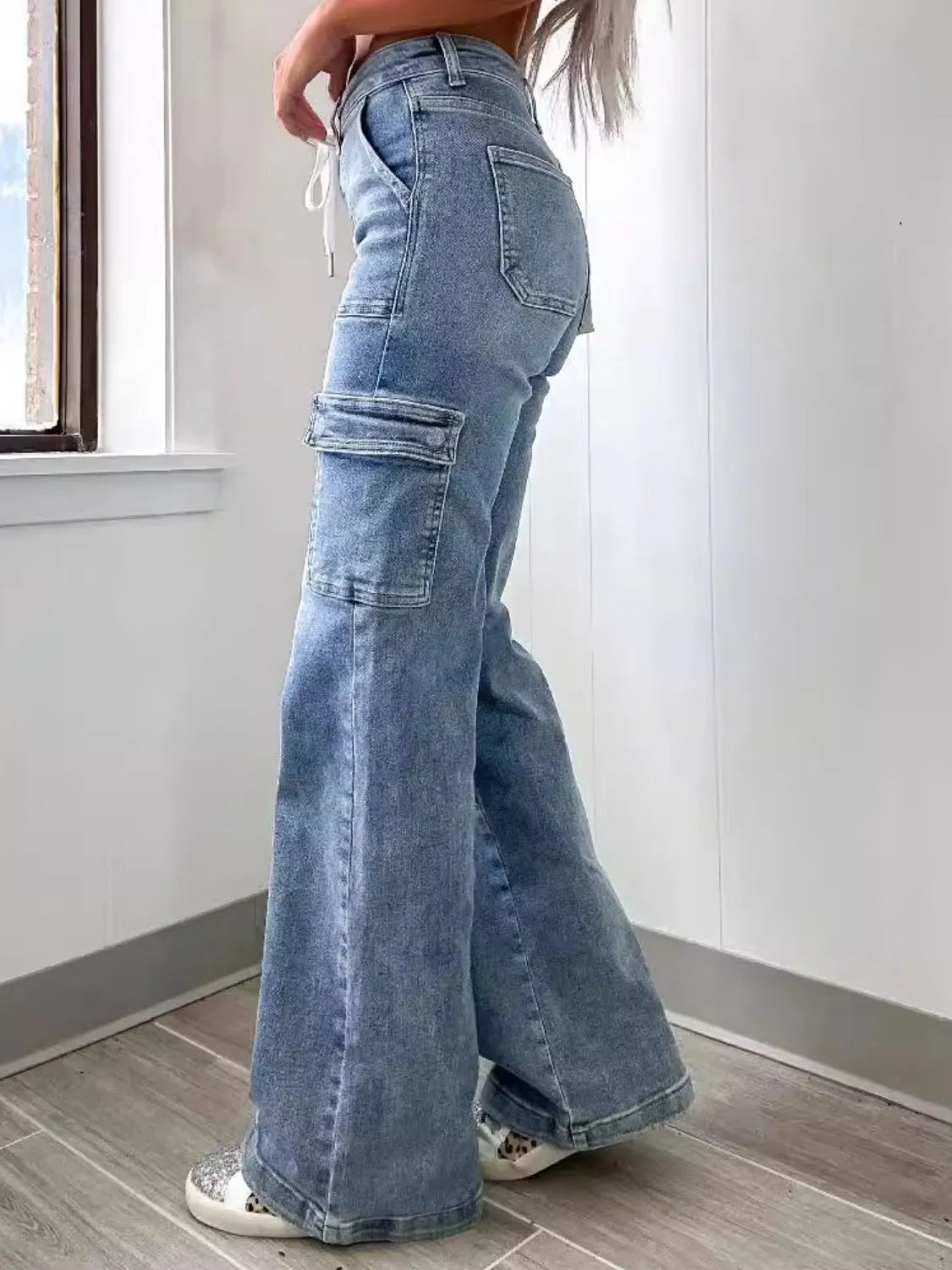 Person wearing light blue flared jeans standing indoors.