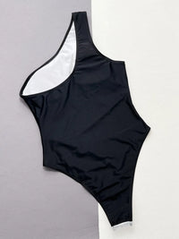 Black one-shoulder swimsuit on a gray background