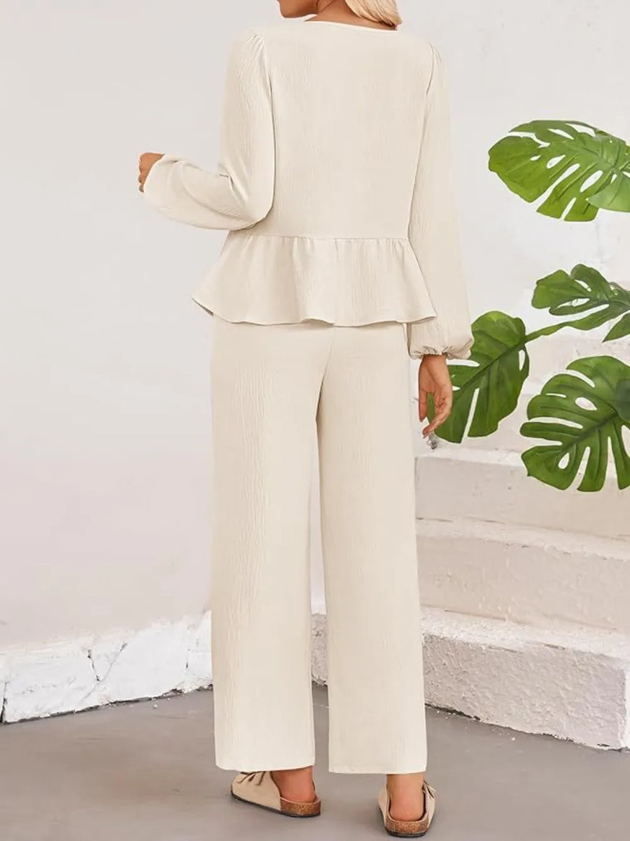 Person wearing a beige outfit with a white wall and green leaves in the background