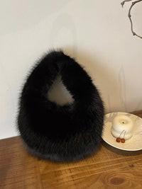 Black fur collar on a wooden surface with a white wall and decorative items in the background.