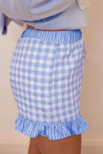 Blue and white checkered skirt with ruffle hem on a beige background