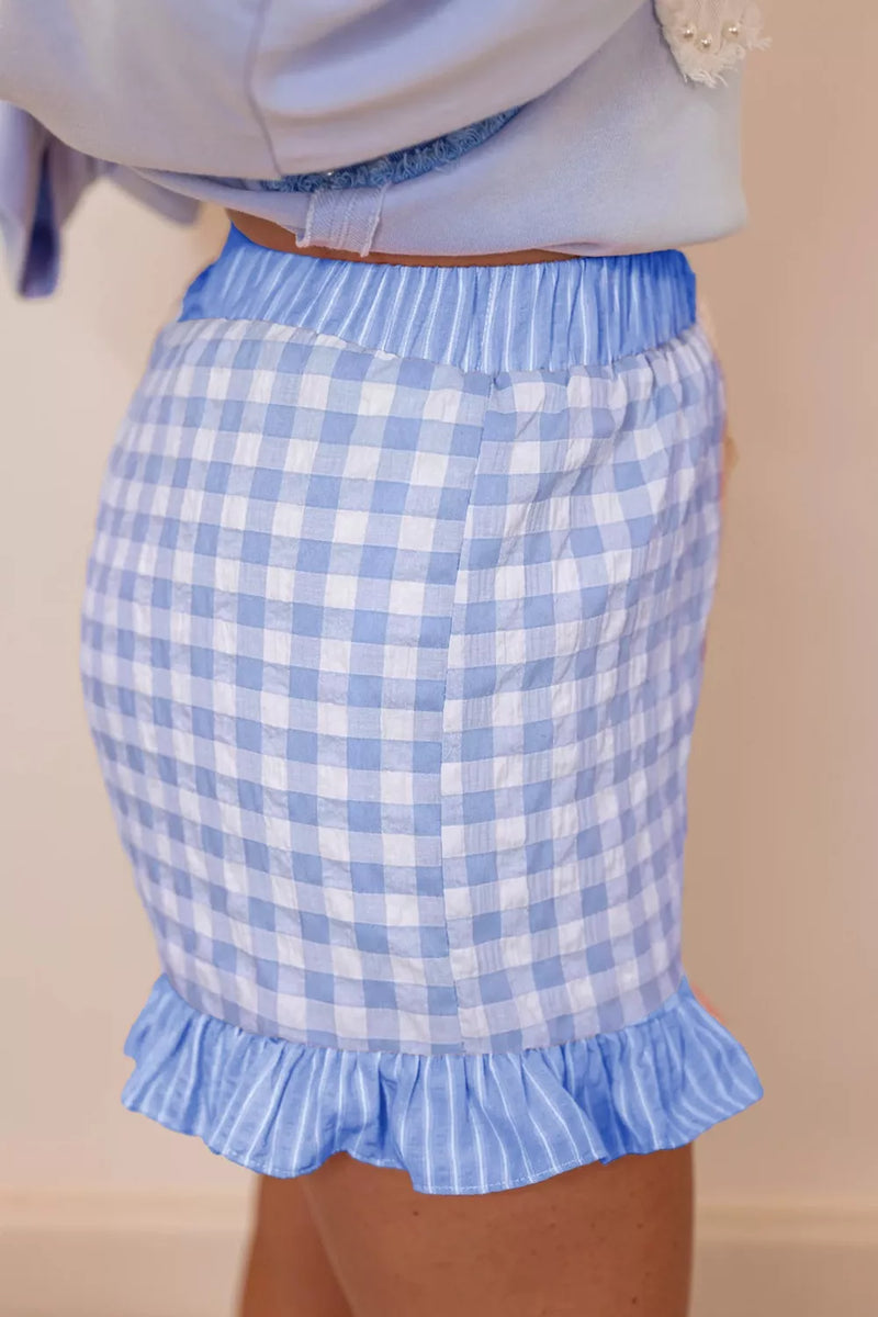 Blue and white checkered skirt with ruffle hem on a beige background