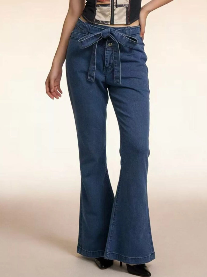 Blue flared jeans worn by a person on a beige background