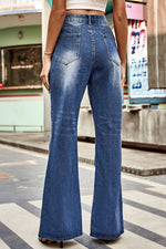 Person wearing blue flared jeans on a city street.