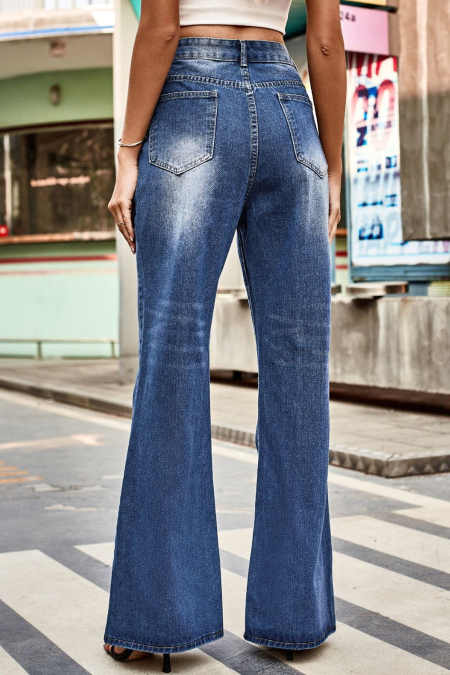 Person wearing blue flared jeans on a city street.