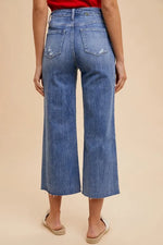 Person wearing blue wide-leg jeans on a beige background