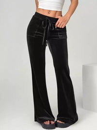Black velvet pants with a tie waist worn by a person on a white background