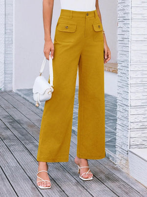 Person wearing mustard yellow wide-leg pants on a wooden deck.