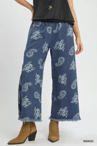 Blue paisley-patterned jeans worn by a person on a white background