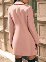 Person wearing a pink coat standing against a textured wall.