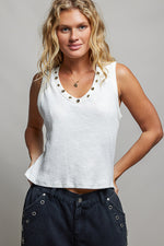 Woman wearing a white tank top with decorative buttons against a gray background