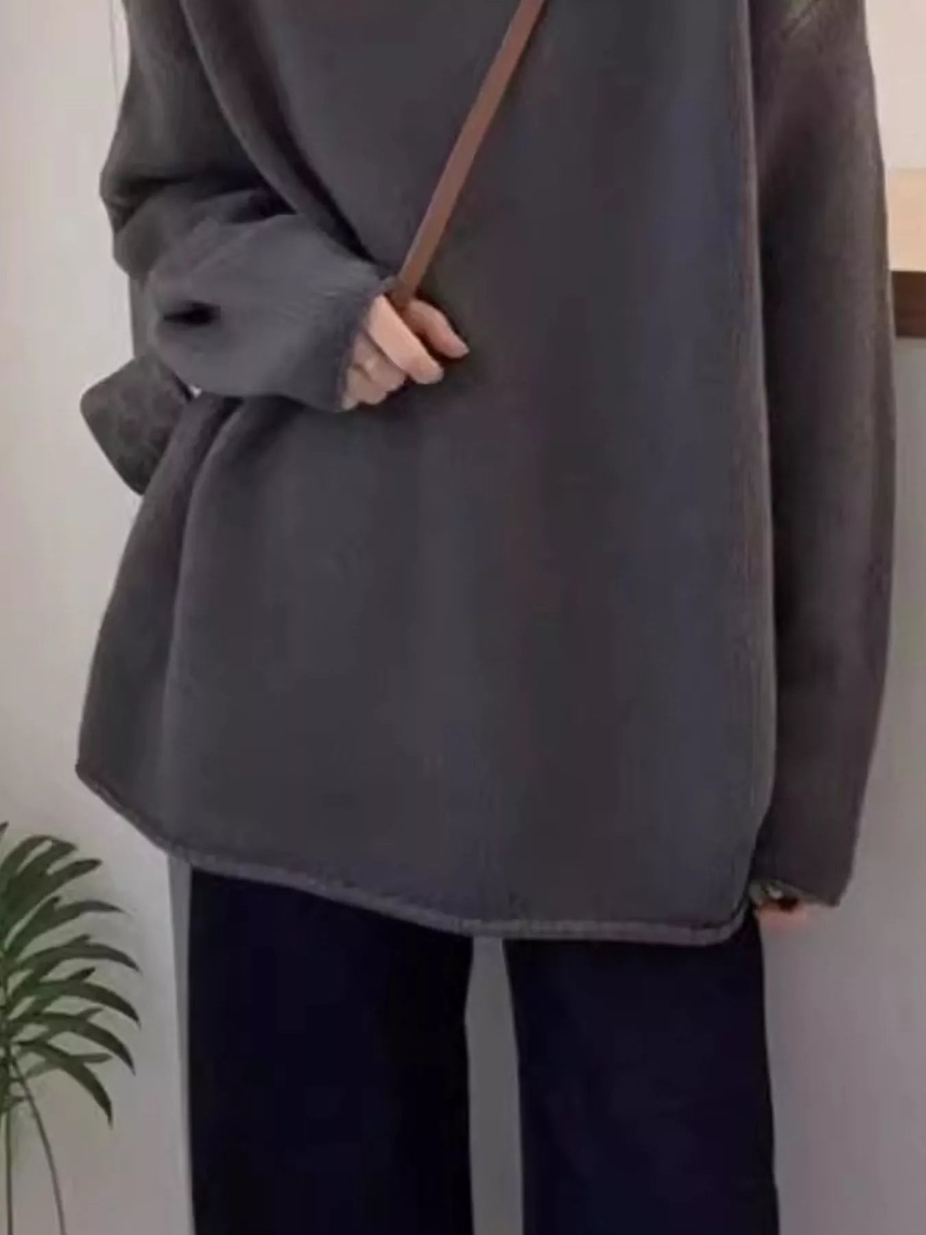 Person wearing a gray coat with a plain background