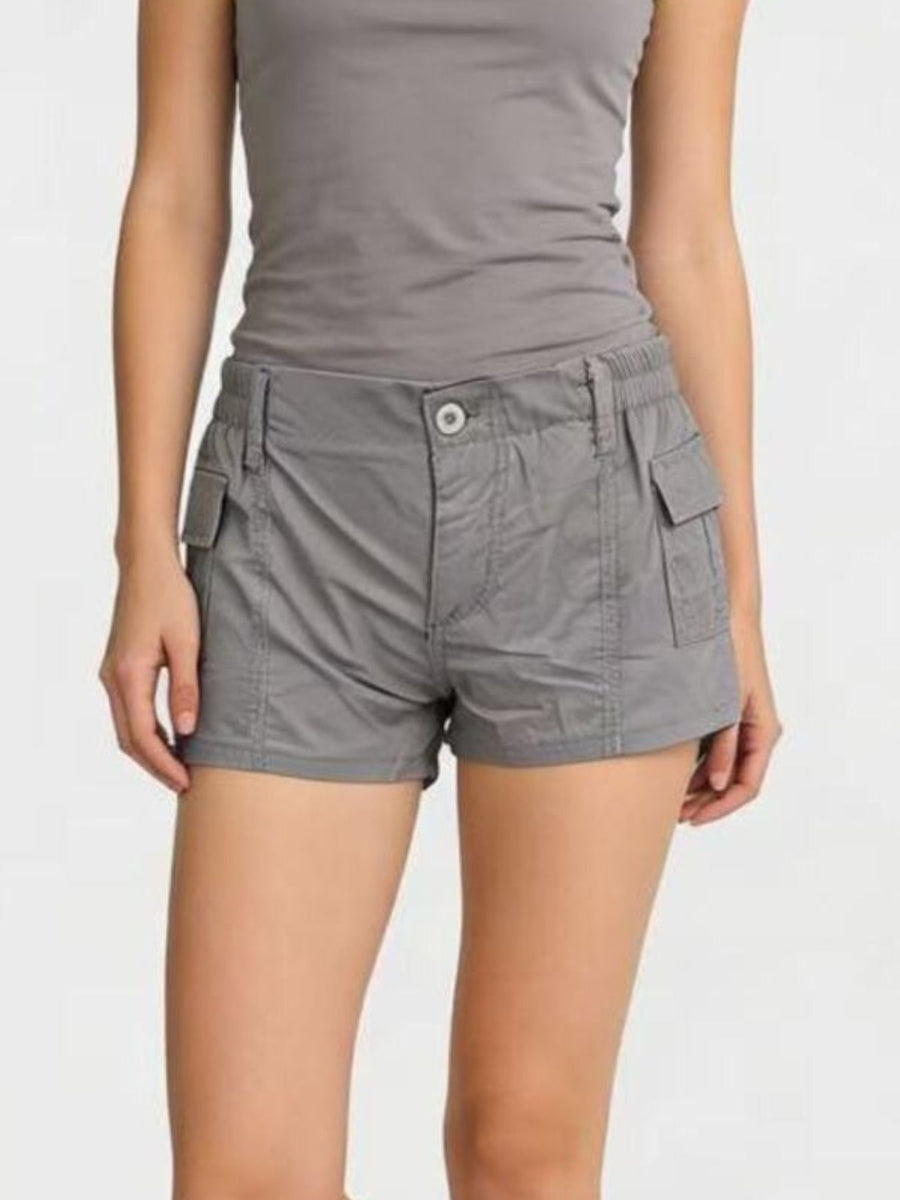 Person wearing gray cargo shorts and tank top on a white background