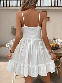 Woman wearing a white dress with thin straps in an outdoor setting.