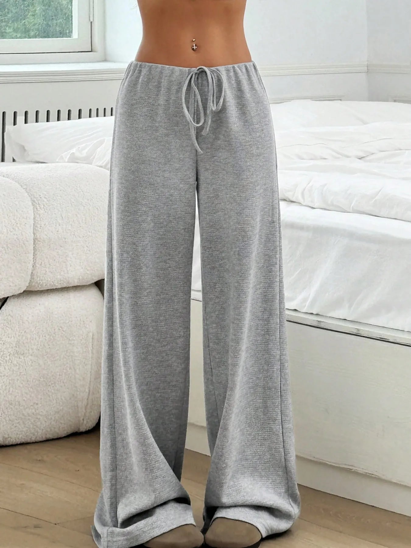 Gray drawstring pants worn by a person in a minimalistic room with a white couch.
