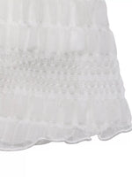 Close-up of a white textured fabric with scalloped edge on a white background