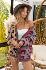 Woman wearing a patterned cardigan over a strapless dress on a balcony.