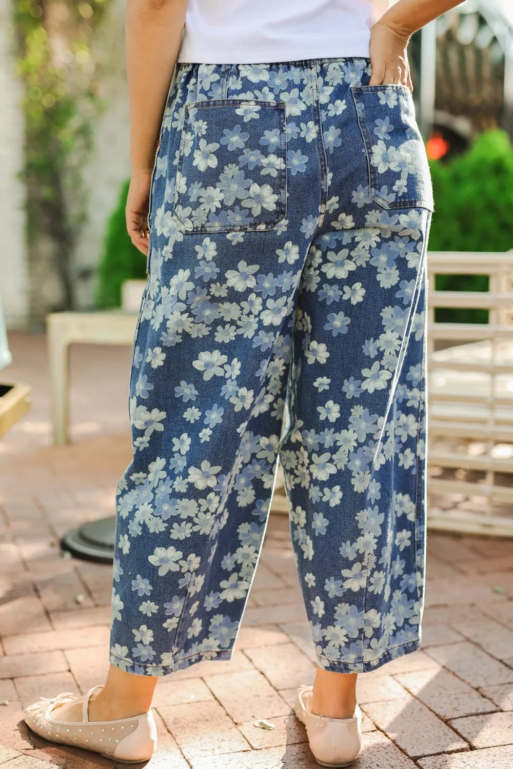 Person wearing blue floral pants standing outdoors on a patio.