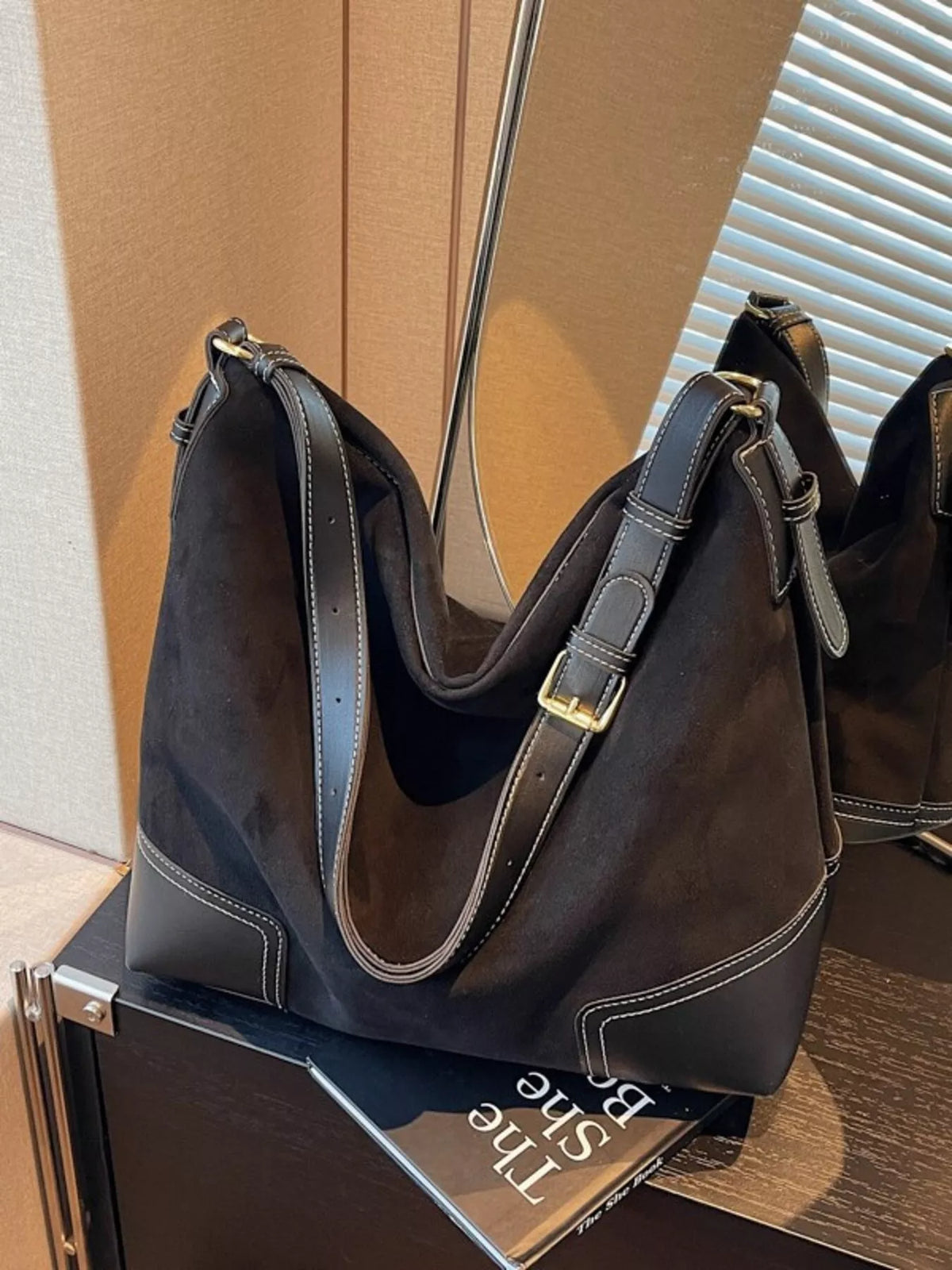 Black handbag on a box with visible branding, against a neutral background