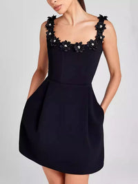 Black dress with floral embellishments on a plain background