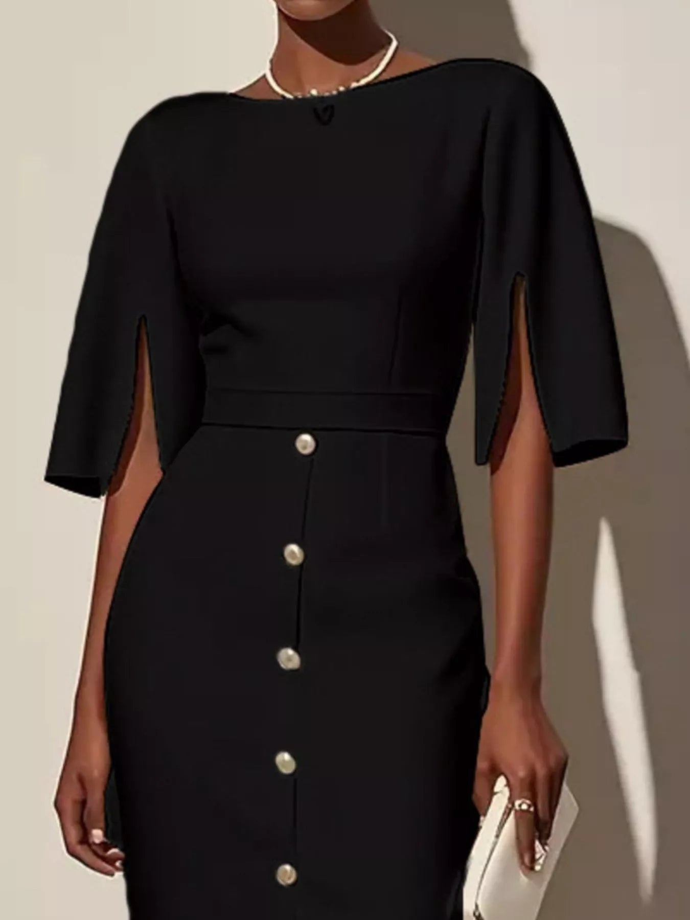 Black dress with button details worn by a model against a neutral background
