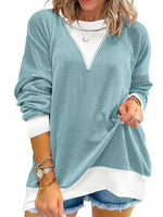 Woman wearing a light blue sweater over a white shirt with denim shorts on a white background