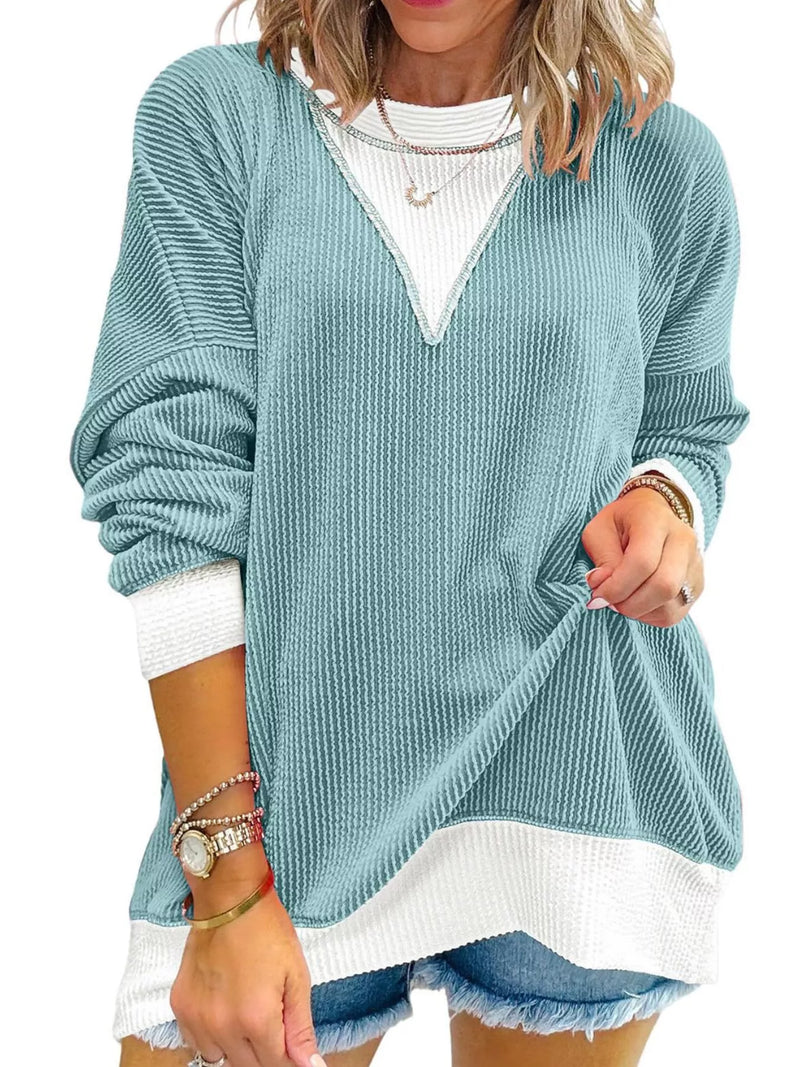 Woman wearing a light blue sweater over a white shirt with denim shorts on a white background