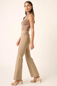 Woman wearing a beige sleeveless top and pants on a white background