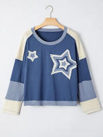 Blue sweater with star designs on a hanger against a white background