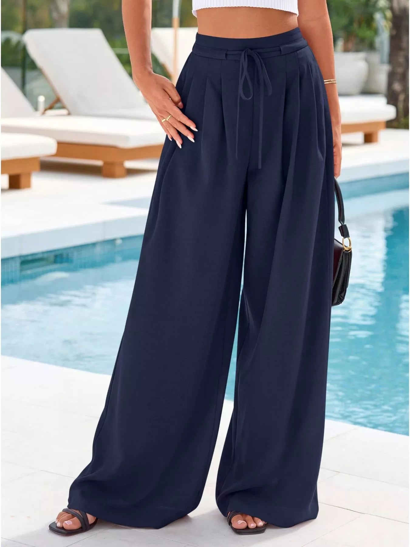 Person wearing navy wide-leg pants by a poolside