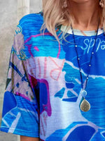 Person wearing a colorful abstract-patterned top with a necklace.