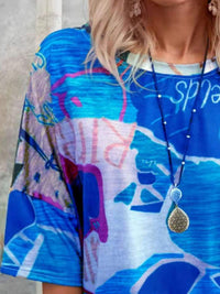 Person wearing a colorful abstract-patterned top with a necklace.
